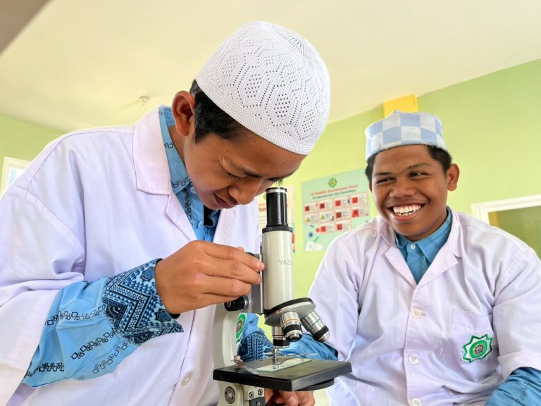 Santri putra Kelas 10 Sains eLKISI mengamati jamur pada tempe busuk menggunakan mikroskop dalam praktikum Biologi.